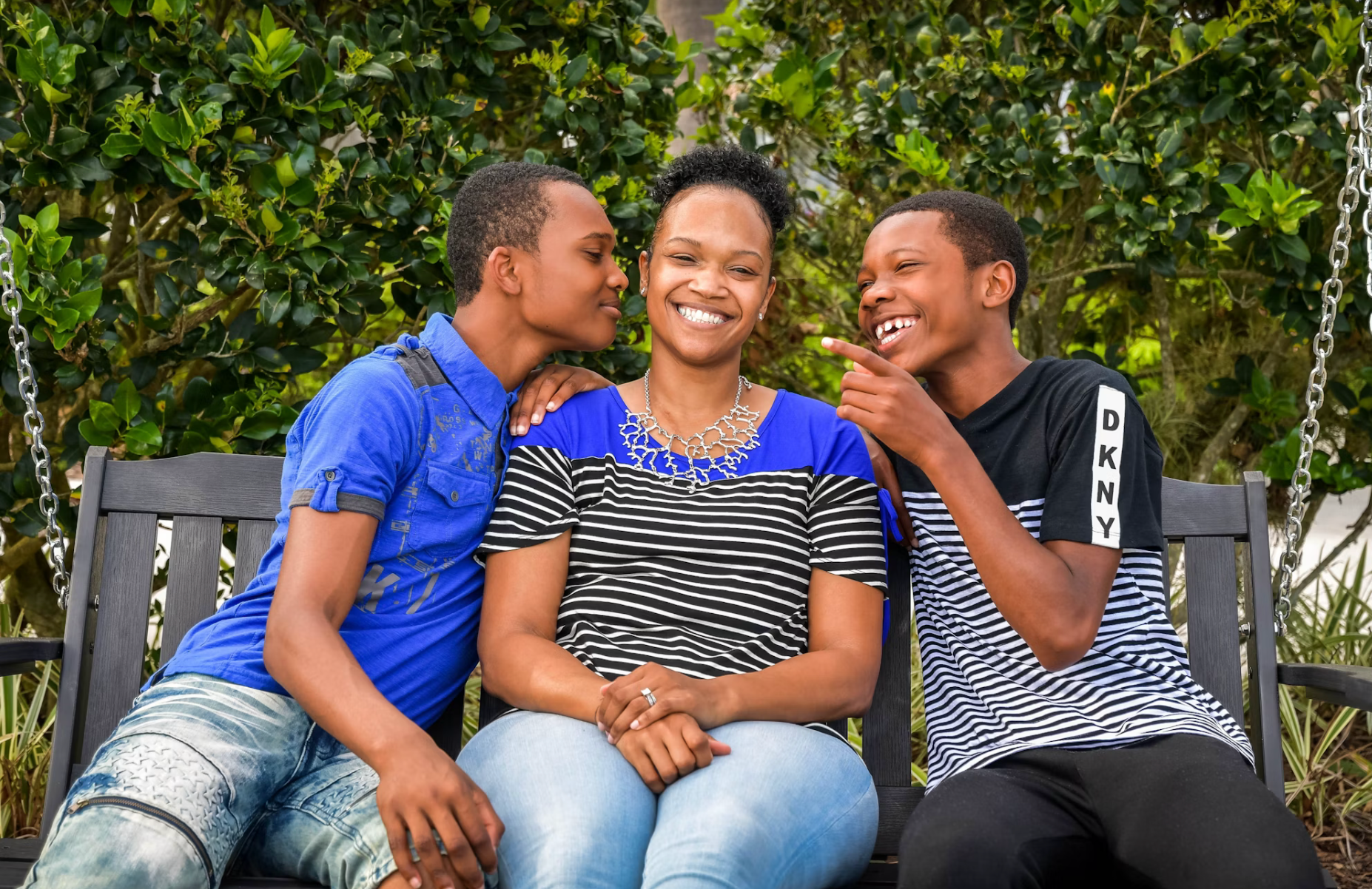A Black mom sitting between her smiling Black sons.
